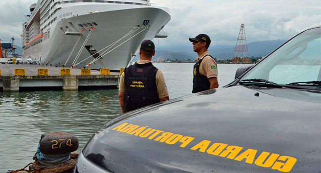 Imagem de dois agentes da guarda portuário, próximos a um navio