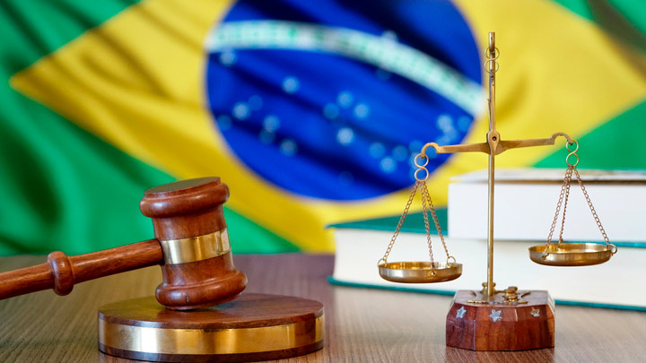 Imagem de um martelo, balança e uma Bandeira do Brasil ao fundo. Alusão ao tema: Legislação Brasileira