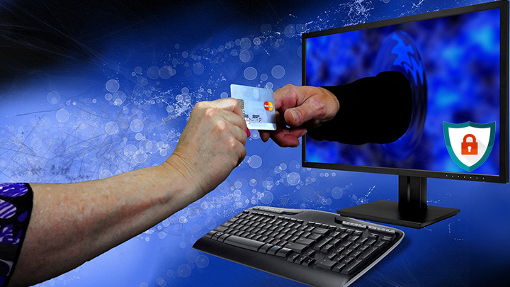 Imagem de uma pessoal com um cartão de crédito e frente a um computador. Alusão a Segurança da Tecnologia da Informção